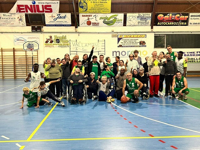 Foto di gruppo a fine partita: giocatori, volontari e accompagnatori posano insieme al centro del campo.